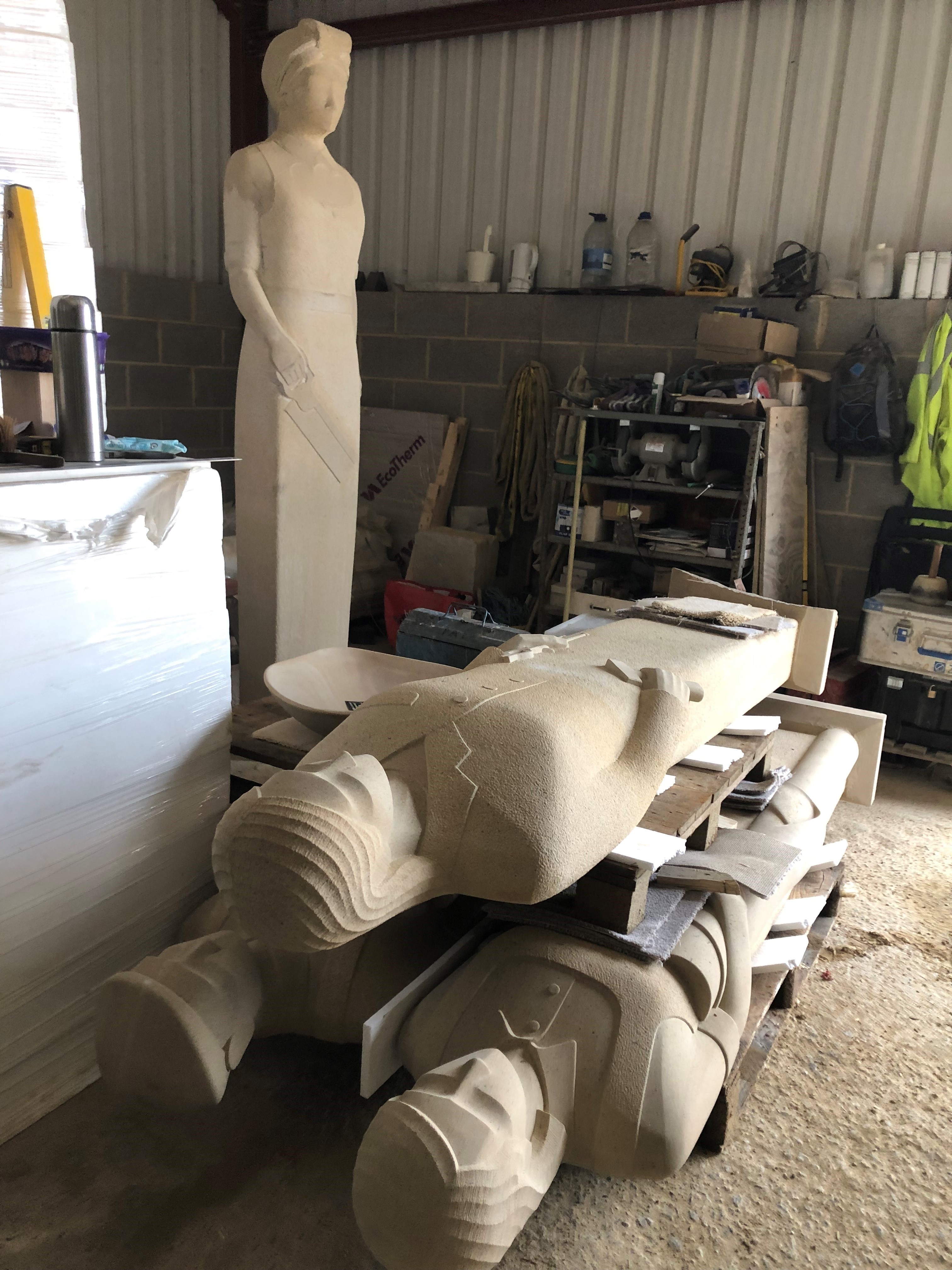 A picture of a workshop with sandstone sculptured human size figures done by Patrick Walls 